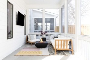 The screened-in patio, featuring a smart television and fire pit, provides the perfect setup for an enjoyable game day experience with friends and family.
