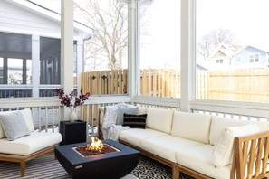 Enjoy the screened-in back patio, featuring a fire pit, outdoor couch, and a smart television, creating the perfect space to enjoy some fresh air. 