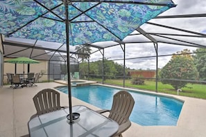 The pool area offers two dining tables, lounge chairs, and a gas BBQ grill. 