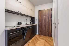 Kitchenette with induction hob, coffee maker, toaster, fridge, kettle, kitchen utensils, dishwasher and oven