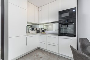 Stylish kitchenette with white furniture and quality appliances. 