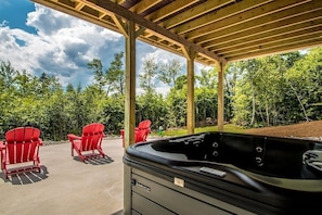 Exterior rear patio with red lounge chairs, hot tub and beautiful mountain views