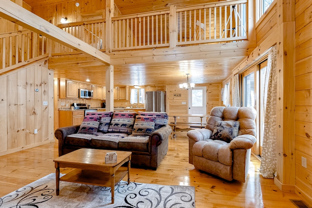 A New Hampshire vacation home has floor to ceiling wood with sunlight streaming through the windows