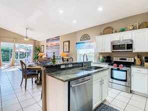 - Whip up delicious meals in this fully stocked kitchen with sleek stainless appliances
- Enjoy snacks or drinks at the granite breakfast bar overlooking the pool area
- Seamless open layout connects kitchen, dining, and patio for easy entertaining