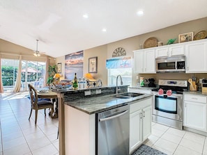 - Whip up delicious meals in this fully stocked kitchen with sleek stainless appliances
- Enjoy snacks or drinks at the granite breakfast bar overlooking the pool area
- Seamless open layout connects kitchen, dining, and patio for easy entertaining