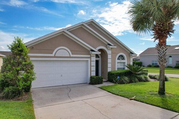 Charming single story home with a clean stucco exterior, manicured lawn, and a welcoming arched entry under Florida’s sunny skies.