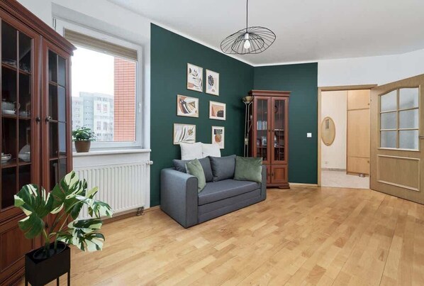A cozy living room with green walls, stylish decor, and a comfortable seating area.
