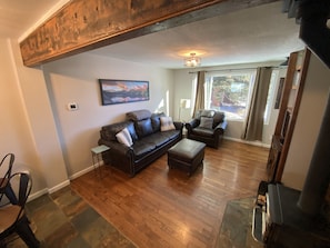 spacious living area with comfy couches, woodstove, and TV.
