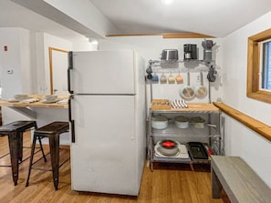 The kitchen includes a spacious refrigerator, pots, pans, a coffee maker, a toaster, and various other kitchen utensils.