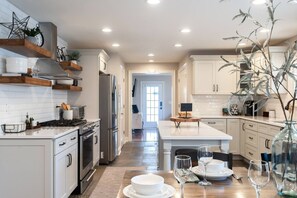 Gas range/oven, new dishwasher, quartz counter tops, and open shelving in the newly remodeled kitchen