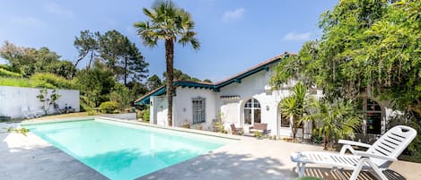 Vue de la terrasse sur la piscine et l'arrière de la maison