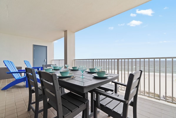 Oversized balcony with 6 person dining table and two Adirondack chairs.