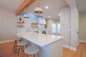 The brand new kitchen features an island with stool seating, white cabinetry and quarter counters.