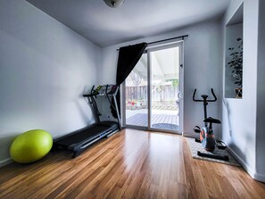 Fitness area with treadmill, bicycle, exercise ball, and dumbbells.