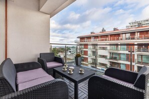  A view of a balcony with a chair, table, and a view of the surrounding area.