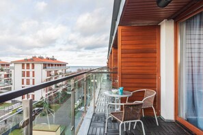 Outdoor balcony area with a small table, chairs, and a view of the surrounding buildings.