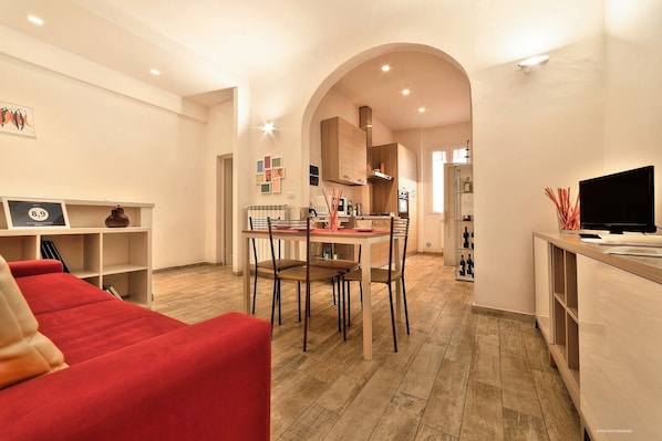 Area soggiorno con divano letto matrimoniale, tavolo con sedie, TV, cucina privata