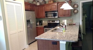 Full kitchen with 3 barstools and stackable washer/dryer in closet.