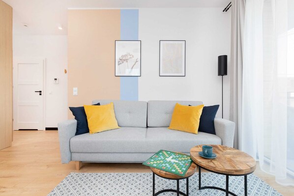A bright living area featuring a cozy gray sofa, yellow cushions, a coffee table, and modern decor.