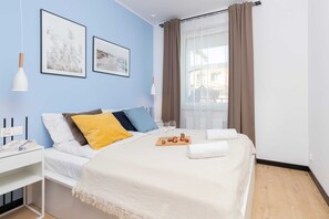 A cozy bedroom with a double bed, light blue walls, and stylish art on the walls.