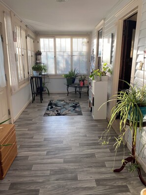 Front porch with live plants with plenty of light to enjoy a quiet day. 