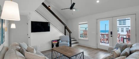 Living room with TV and ceiling fan and access to the staircase