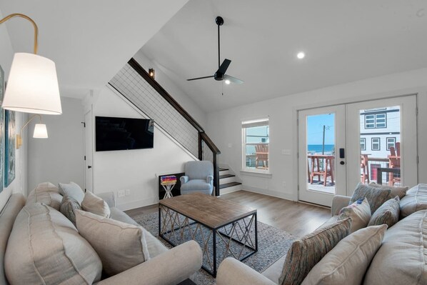 Living room with TV and ceiling fan and access to the staircase