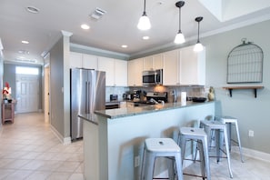 Kitchen - The spacious kitchen offers an eat-in style bar with seating for 4. Stainless appliances are featured in this open space and include a side by side refrigerator, gas stove, built in microwave, ice maker, wine cooler and dishwasher