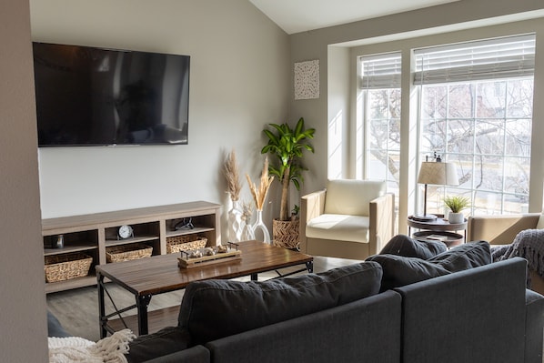 Family room with giant bay window. 63 inch Smart TV. Huge sectional 