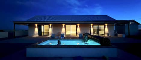 north elevation at night, lighted and heated pool.
