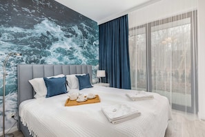 Bedroom with a double bed, featuring a blue accent wall, blue bedding, and a bedside lamp.