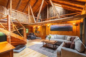Kick back in the heart of the cabin—our cozy great room features a plush sectional, soaring log beams, and a handcrafted spiral staircase that’s as charming as it is unique.