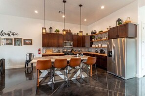 Barstool seating at the kitchen island offers a perfect blend of functionality and style. It highlights rustic elements and is adorned with sleek, modern fixtures.