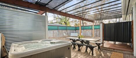 Shaded private backyard with hot tub, picnic table, & outdoor shower