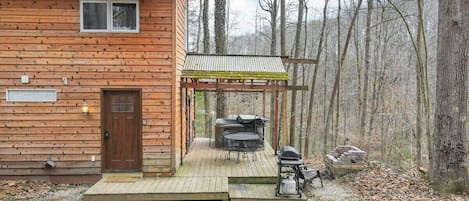 Deck off the side of the cabin with seating, a grill, fire pit area, and hot tub