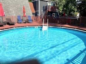 Shared 24' diameter outdoor above-ground pool with deck and chaise lounge chairs