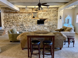 Two seat bar looking at the TV on exposed stone wall.