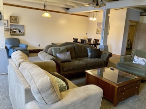 Open concept living space features seating group, dining table and lone chair.