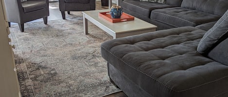 Bright open living room with sectional, two chairs and beautiful views. 