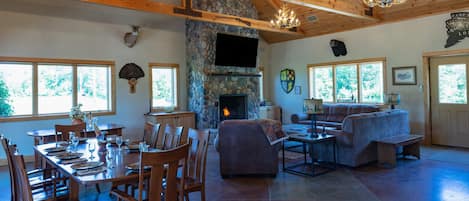 Great Room with large stone fireplace and cherry dining tables for 14 guests.