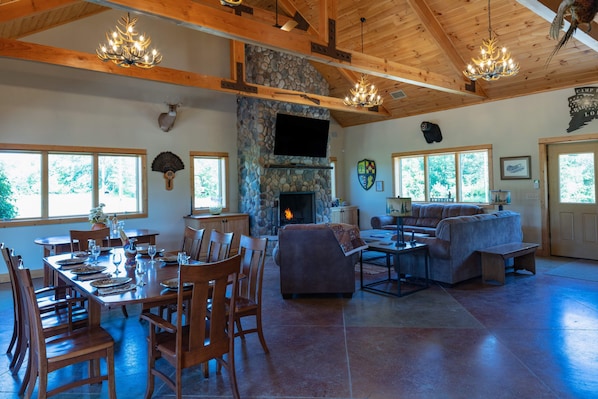 Great Room with large stone fireplace and cherry dining tables for 14 guests.