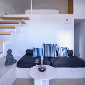 Living area with sofa and coffee table. Staircase to the 1st bedroom