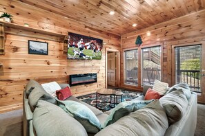 Kick back in this cozy cabin-style living room — with a big-screen TV, electric fireplace, and plush seating perfect for game night or movie marathons 🎬🔥