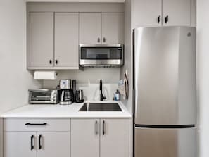 Fridge, freezer, microwave, coffee machine toaster oven, hotplate, & cookware. 