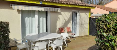 Pavillon de plain pied adossé à la forêt, avec terrasse et salon de jardin.