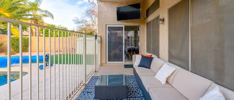 Gated outdoor patio with lounge seating and streaming tv.
