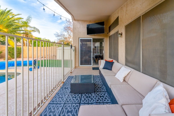 Gated outdoor patio with lounge seating and streaming tv.