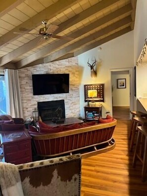 Sloped wooden ceiling accentuates good energy. This living room exudes relaxation and family fun.