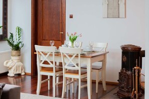 Dining area with a white table and chairs, complemented by a simple indoor plant and natural lighting.