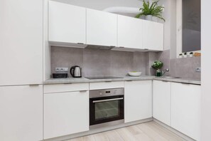 A stunning kitchen design featuring white cabinets with brass handles, a pristine white tiled backsplash, and open shelving for an organized and stylish look. Ideal for cooking enthusiasts seeking both functionality and aesthetics.